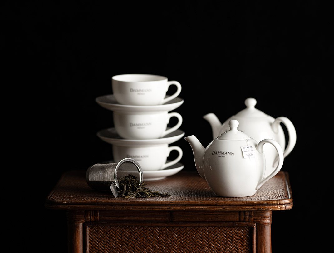 White teapots, cups and a tea infuser on a wooden table