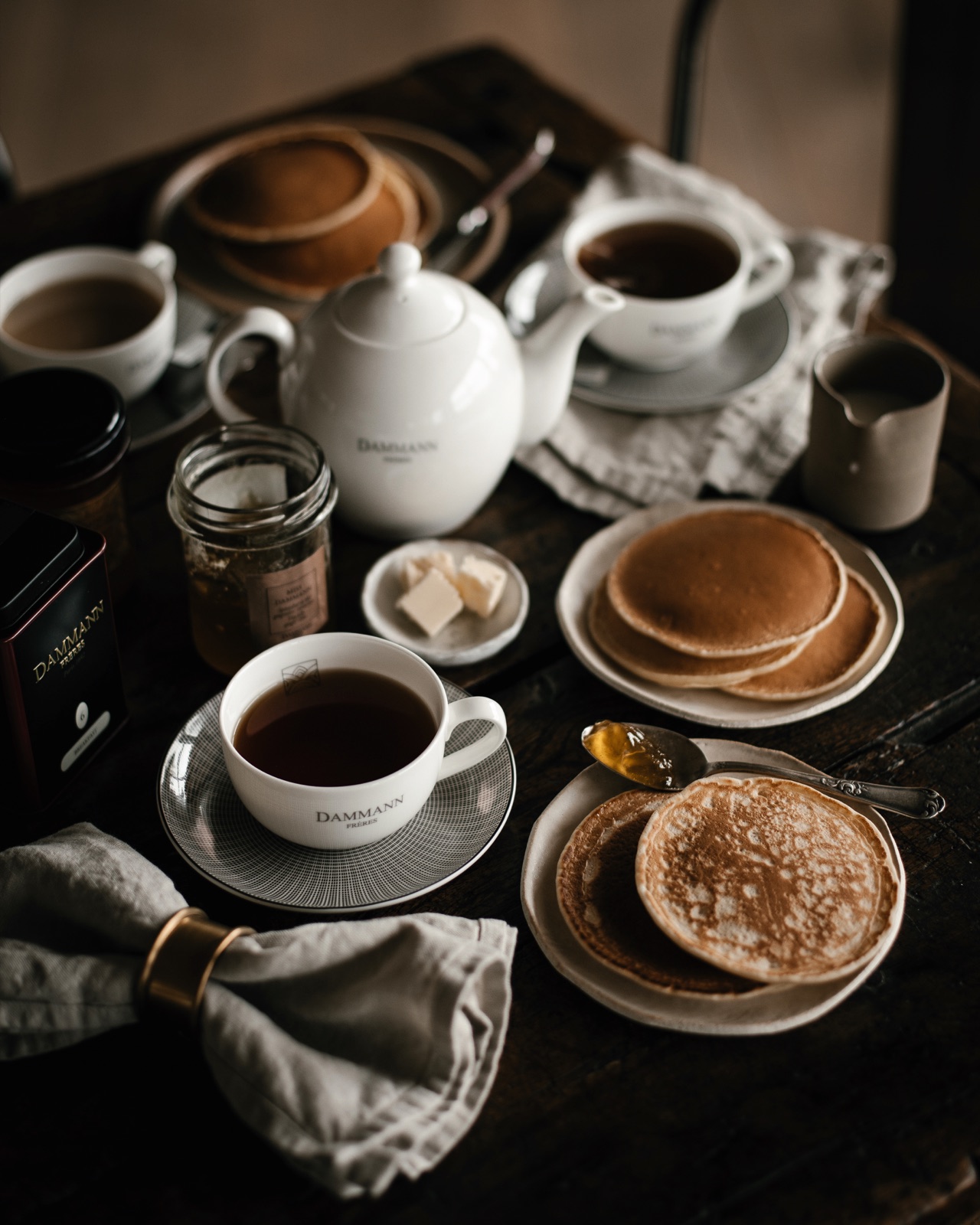 Teapot, tea cups and pancakes on a breakfast table